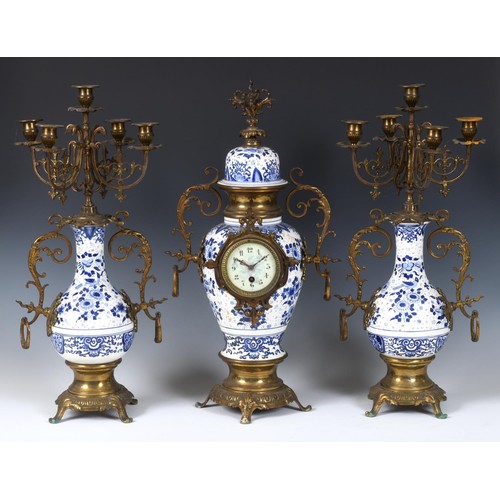 192 - A clock garniture, the 8 cm diameter dial with Arabic numerals, in a pottery and gilt metal mounted ... 