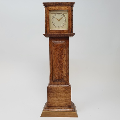 197 - A timepiece, the 4.5 cm square dial in an oak case, in the form of a longcase clock, 29.5 cm high