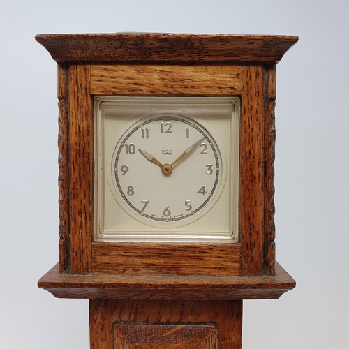 197 - A timepiece, the 4.5 cm square dial in an oak case, in the form of a longcase clock, 29.5 cm high