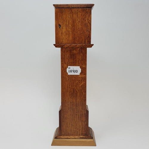 197 - A timepiece, the 4.5 cm square dial in an oak case, in the form of a longcase clock, 29.5 cm high