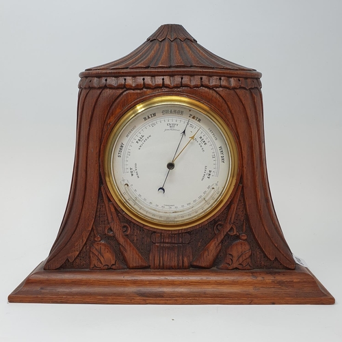 207 - An early 20th century barometer and thermometer, in an oak case carved two guns and two pickelhaubes... 