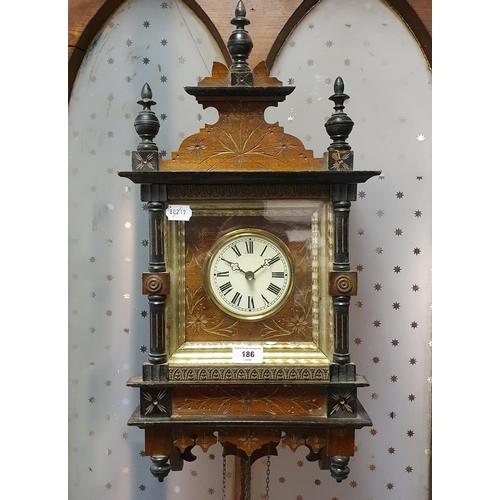 186 - A wall clock, the 10 cm diameter dial with Roman numerals, in a walnut and ebonised case, 65 cm high