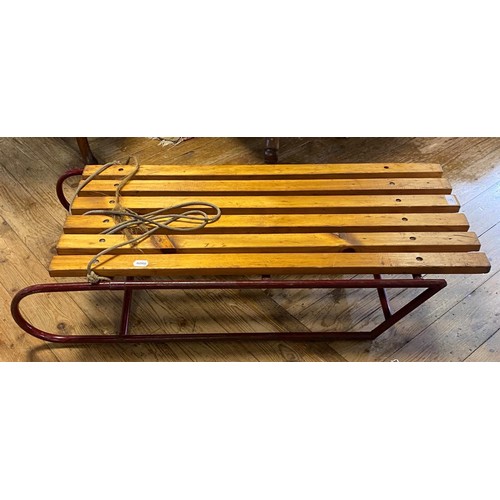 57 - A sledge, with wooden slats on a red painted metal frame, 107 cm