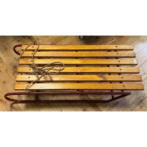 57 - A sledge, with wooden slats on a red painted metal frame, 107 cm