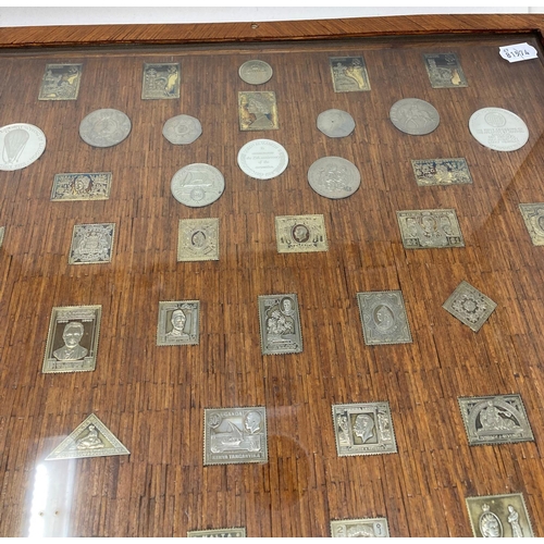 129 - A set of silver postage stamp coin medallions, and other medallions, set in a frame constructed from... 