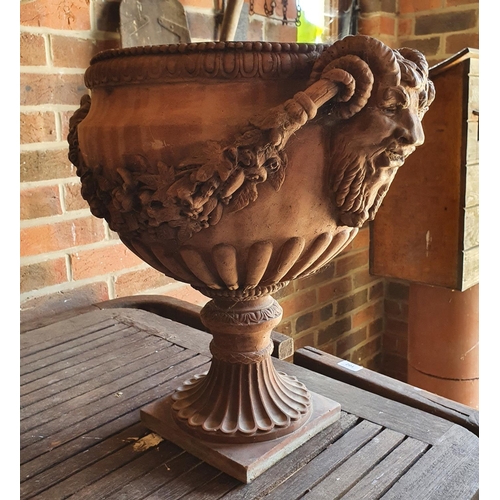 101 - An earthenware style garden urn, decorated face masks and foliage, 46 cm high (in the entrance porch... 