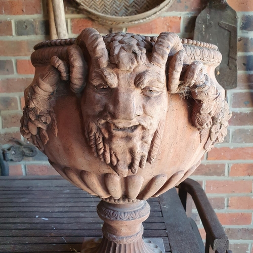 101 - An earthenware style garden urn, decorated face masks and foliage, 46 cm high (in the entrance porch... 