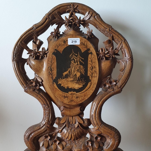 219 - A late 19th century Austrian musical chair, carved edelweiss and other foliage, and inlaid with a hu... 