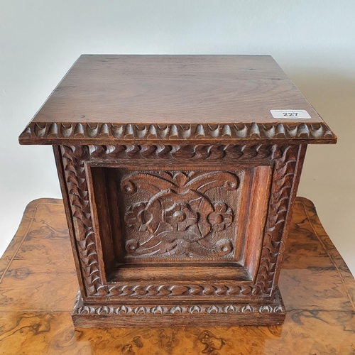 227 - A late Victorian carved oak cabinet, having a panel door opening to reveal three drawers, on a plint... 