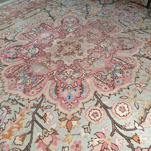 250 - A Persian style carpet, decorated flowers and foliage on a green ground, within a pink border, 305 x... 