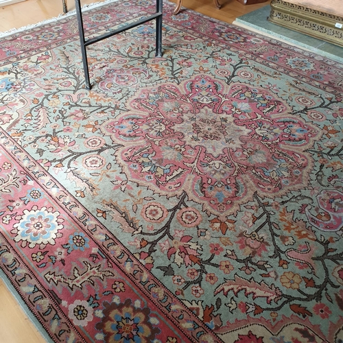 250 - A Persian style carpet, decorated flowers and foliage on a green ground, within a pink border, 305 x... 