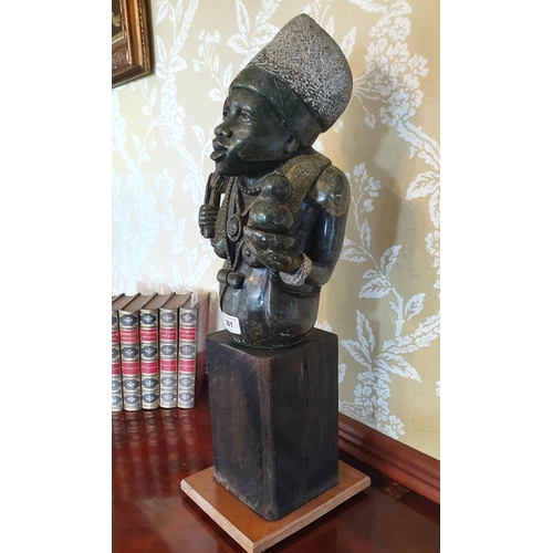 261 - An African carved stone figure, 34 cm high, on a stand, 56 cm high (overall)