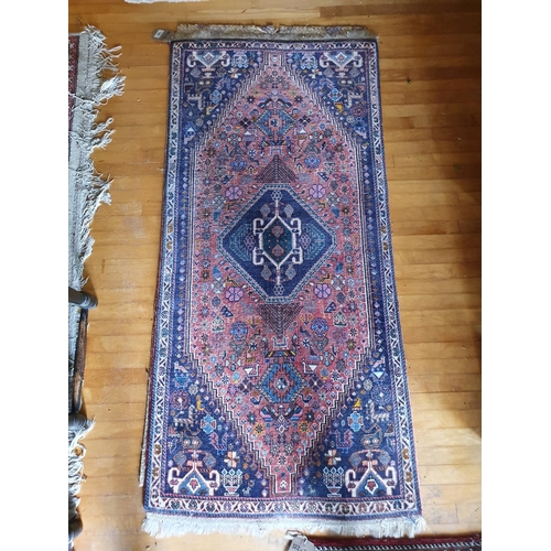 320 - A small Persian rug, with a central lozenge on a salmon pink ground, 145 x 70 cm, and another simila... 