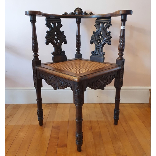 335 - A late 19th century carved walnut corner armchair, decorated a cherub face mask and scrolling foliag... 