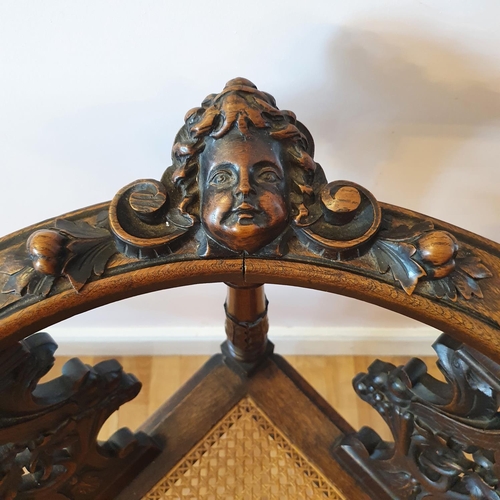 335 - A late 19th century carved walnut corner armchair, decorated a cherub face mask and scrolling foliag... 