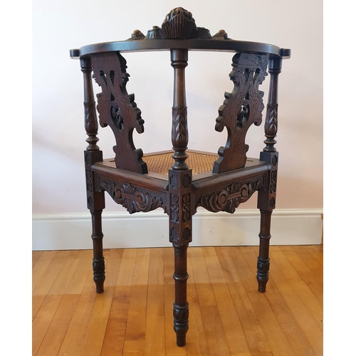 335 - A late 19th century carved walnut corner armchair, decorated a cherub face mask and scrolling foliag... 