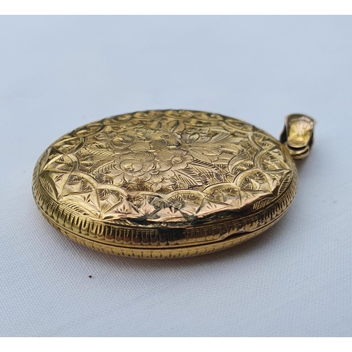 351 - A yellow coloured metal oval pendant, with engraved decoration