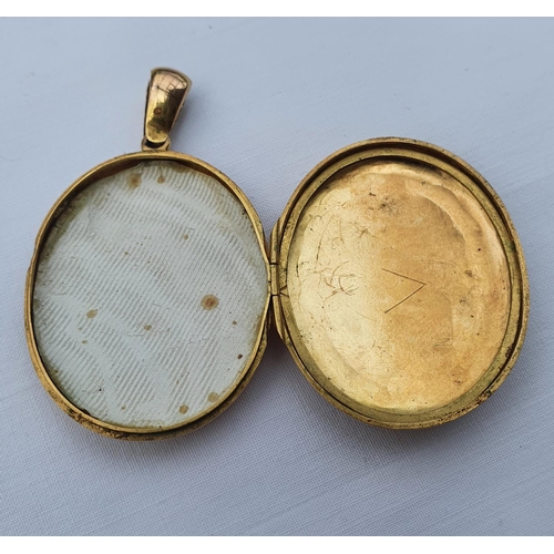 351 - A yellow coloured metal oval pendant, with engraved decoration