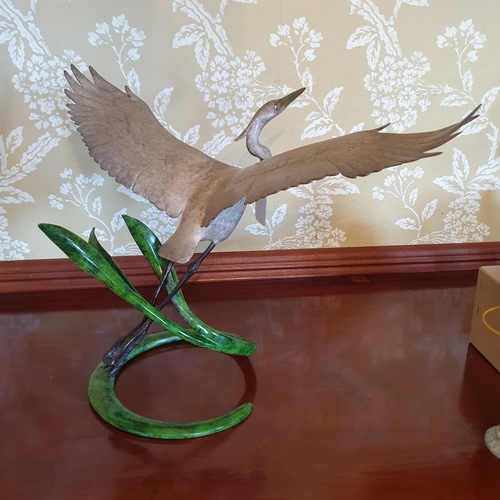 447 - A patinated bronze figure of a stork in flight, 33 cm high x 51 cm wingspan