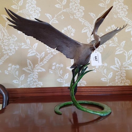 447 - A patinated bronze figure of a stork in flight, 33 cm high x 51 cm wingspan