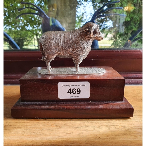 469 - A modern silver figure of a ram, mounted on a wooden base, 11 cm high