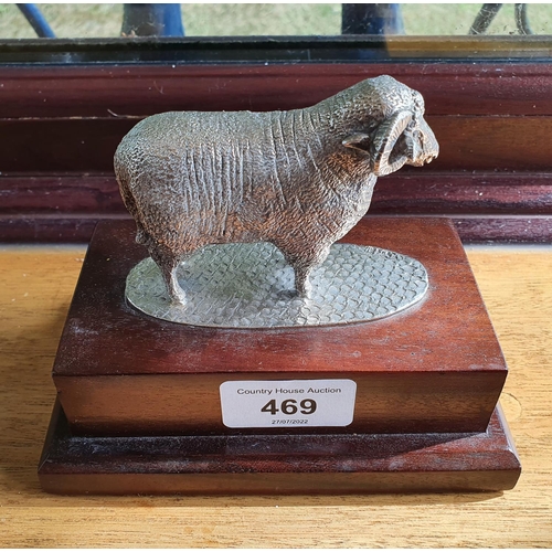 469 - A modern silver figure of a ram, mounted on a wooden base, 11 cm high