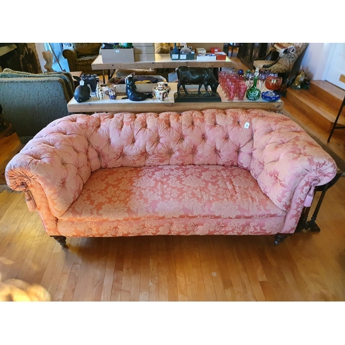 485 - A late Victorian button back upholstered Chesterfield settee, on turned front legs and later castors... 