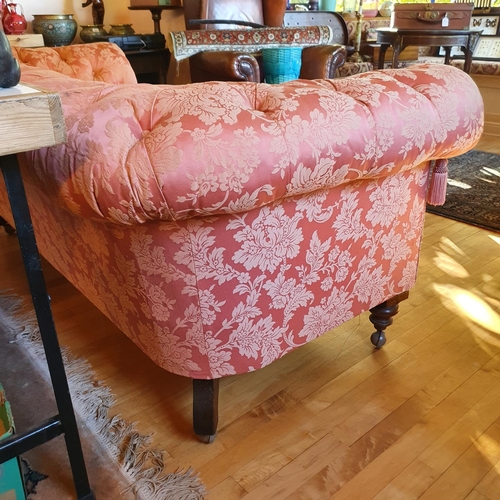 485 - A late Victorian button back upholstered Chesterfield settee, on turned front legs and later castors... 