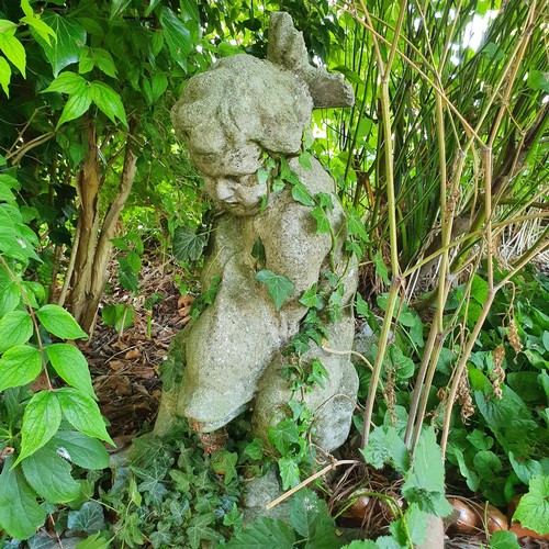 69 - A reconstituted stone garden fountain, in the form of a child holding a dolphin, approx. 65 cm high