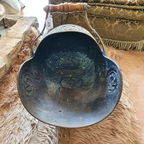 479 - A Victorian brass helmet shaped coal scuttle, with embossed decoration, a shovel, with a set of thre... 