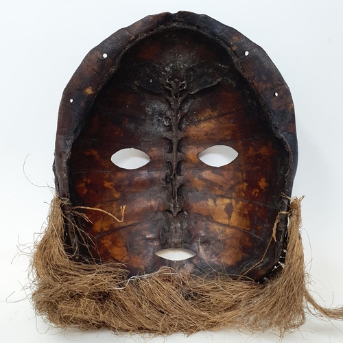 583 - A turtle carapace tribal mask, pierced and decorated shells, 28 cm high