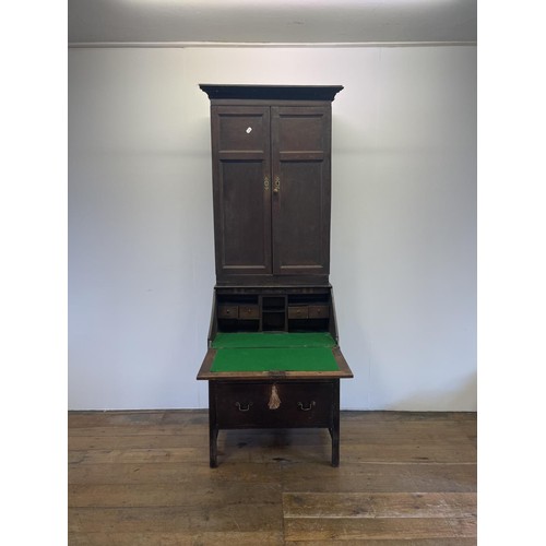 754 - An oak bureau bookcase, the top having two cupboard doors, above a fall front with a fitted interior... 