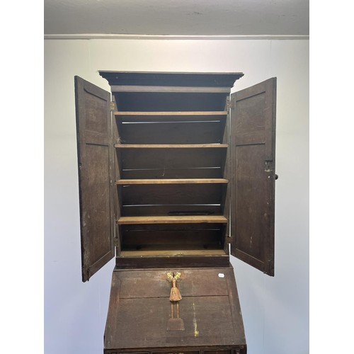 754 - An oak bureau bookcase, the top having two cupboard doors, above a fall front with a fitted interior... 