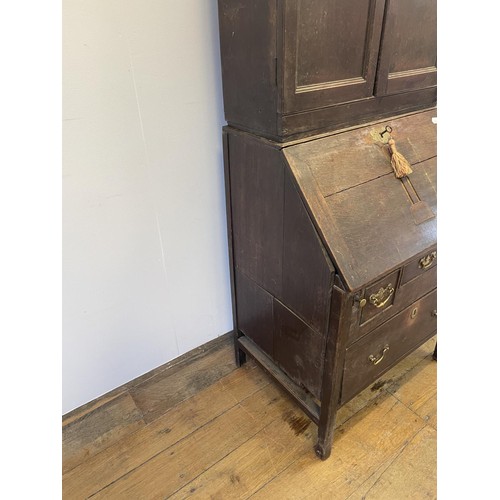 754 - An oak bureau bookcase, the top having two cupboard doors, above a fall front with a fitted interior... 