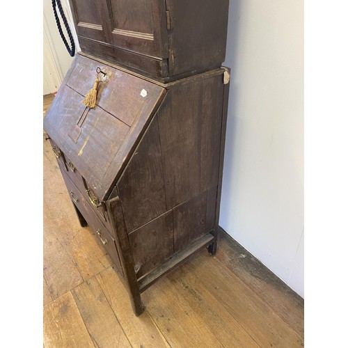 754 - An oak bureau bookcase, the top having two cupboard doors, above a fall front with a fitted interior... 