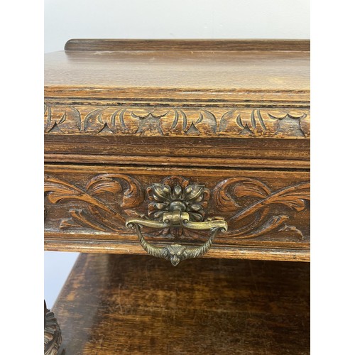 773 - An oak buffet, the top having two drawers, above an open section, above two cupboard doors, carved w... 