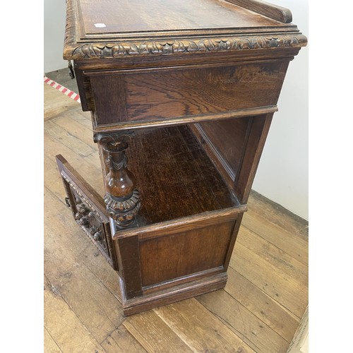 773 - An oak buffet, the top having two drawers, above an open section, above two cupboard doors, carved w... 