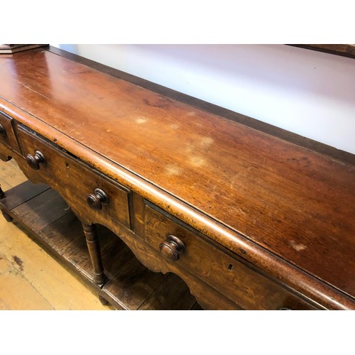 783 - An oak dresser, having a later two tier plate rack above a base with three frieze drawers and a potb... 