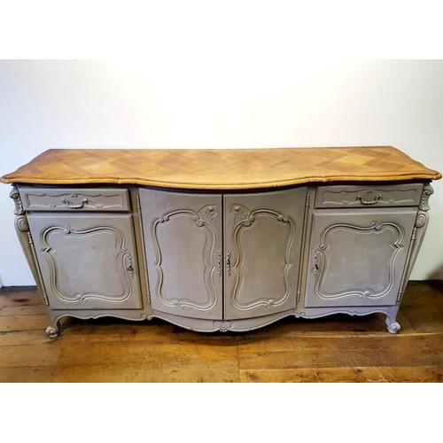 486 - A French oak serpentine sideboard, with a painted front, having two cupboard doors, flanked by two d... 