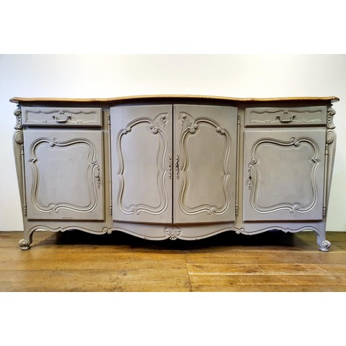 486 - A French oak serpentine sideboard, with a painted front, having two cupboard doors, flanked by two d... 