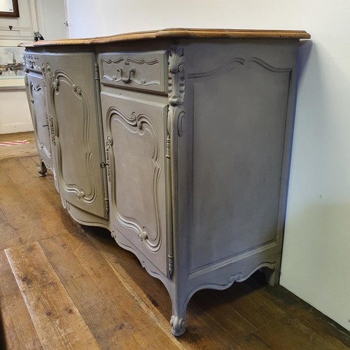 486 - A French oak serpentine sideboard, with a painted front, having two cupboard doors, flanked by two d... 