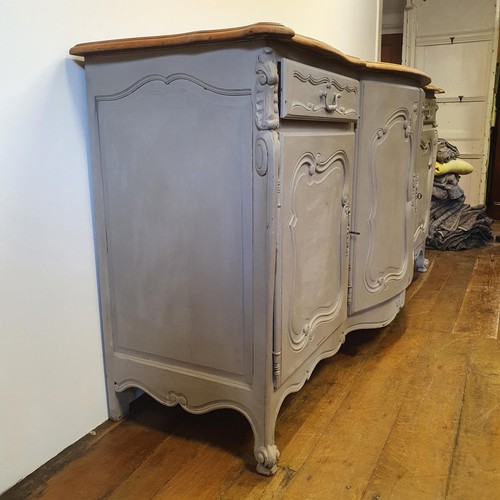 486 - A French oak serpentine sideboard, with a painted front, having two cupboard doors, flanked by two d... 