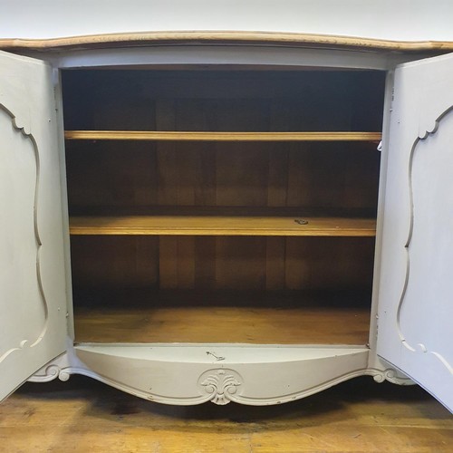 486 - A French oak serpentine sideboard, with a painted front, having two cupboard doors, flanked by two d... 