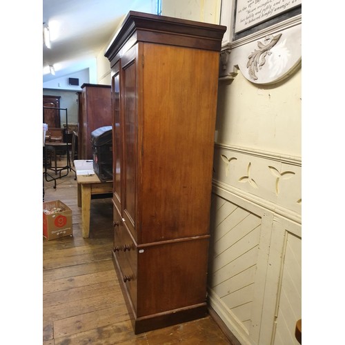 573 - A 19th Century mahogany linen press, two cupboard doors to reveal shelves, on a base with two drawer... 