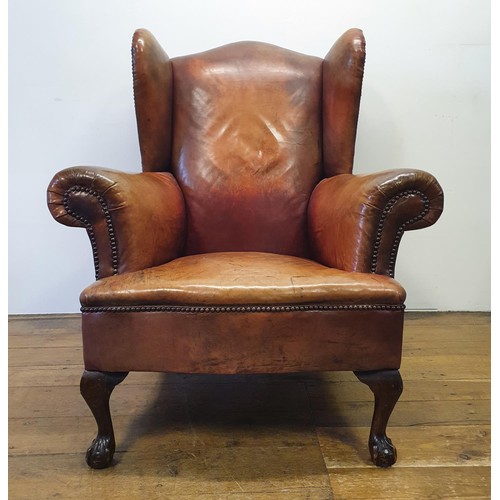 537 - A George III style wing armchair, upholstered in leather, on cabriole front legs, with claw and ball... 