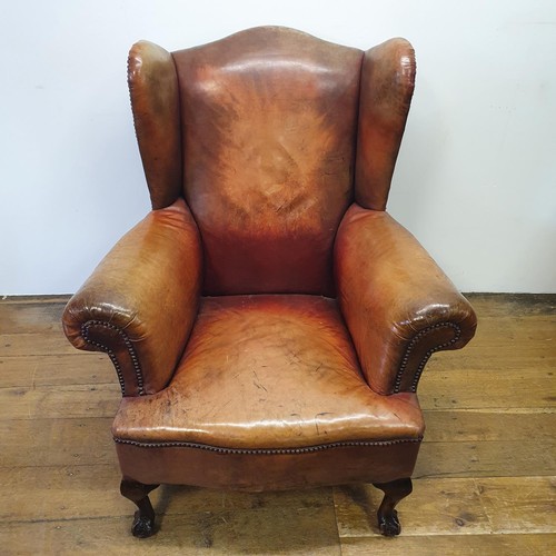 537 - A George III style wing armchair, upholstered in leather, on cabriole front legs, with claw and ball... 