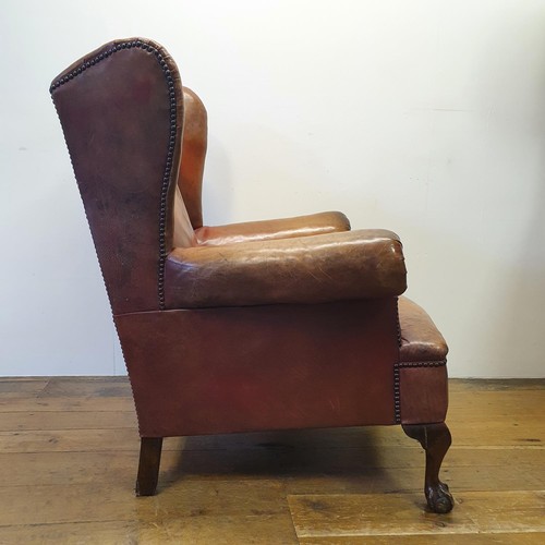 537 - A George III style wing armchair, upholstered in leather, on cabriole front legs, with claw and ball... 