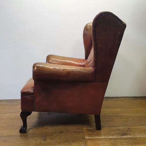 537 - A George III style wing armchair, upholstered in leather, on cabriole front legs, with claw and ball... 