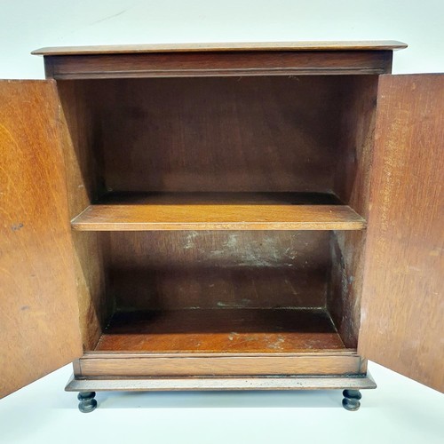 389 - An early 20th century walnut table top two door cabinet, on turned feet, 31 cm wide