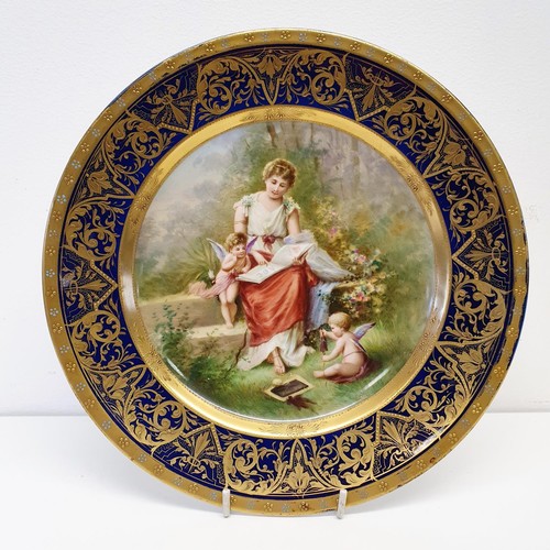 423 - A Vienna porcelain plate, Amors Studium, within a blue and gilt border, 24.5 cm diameter